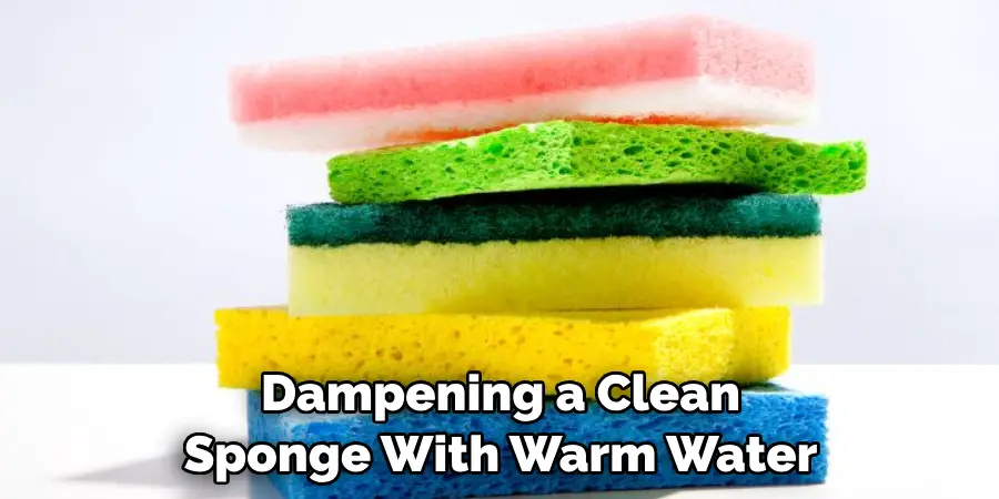Dampening a Clean Sponge With Warm Water